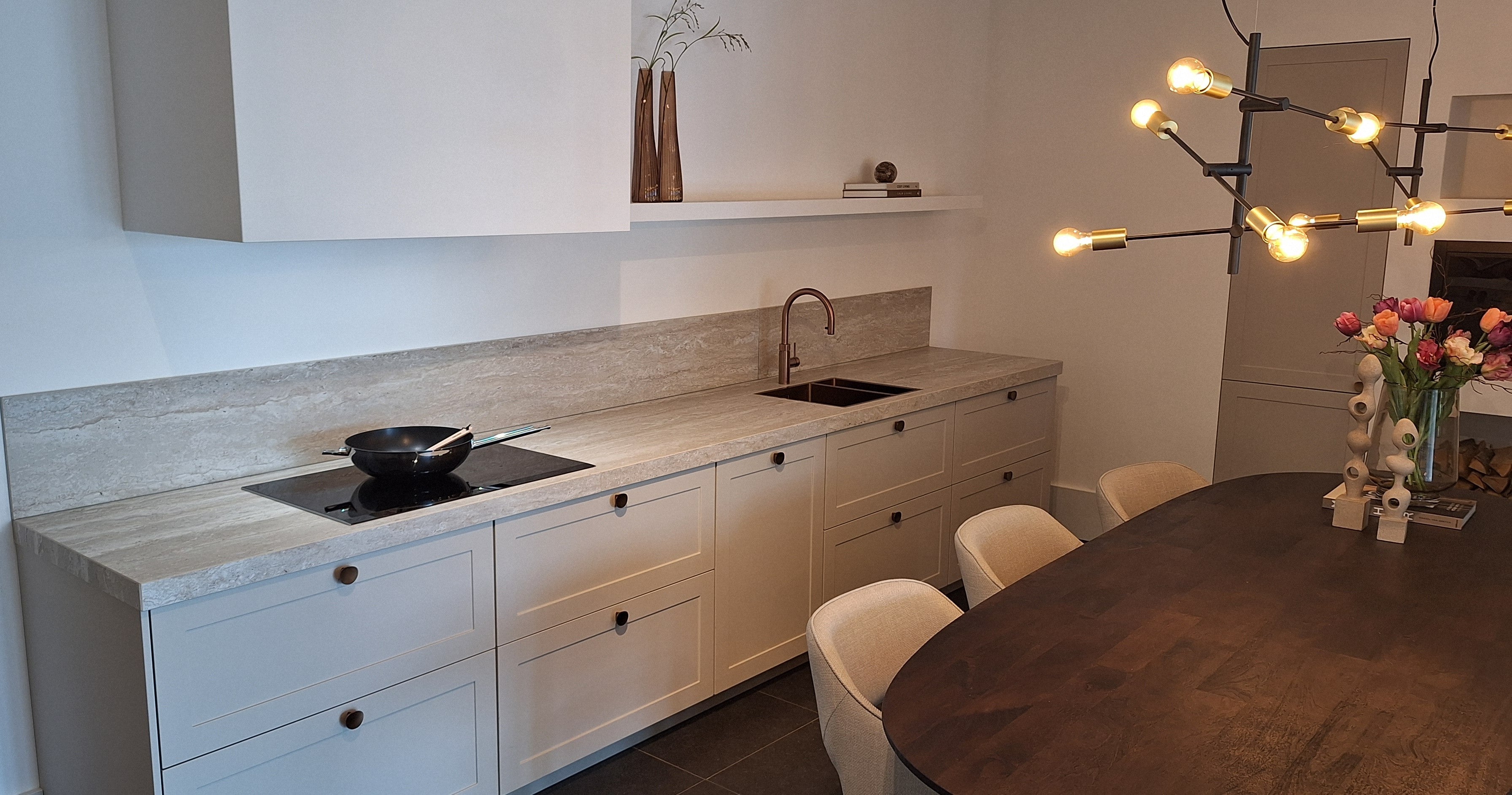 Lichte keuken met travertin keukenblad en koperen details