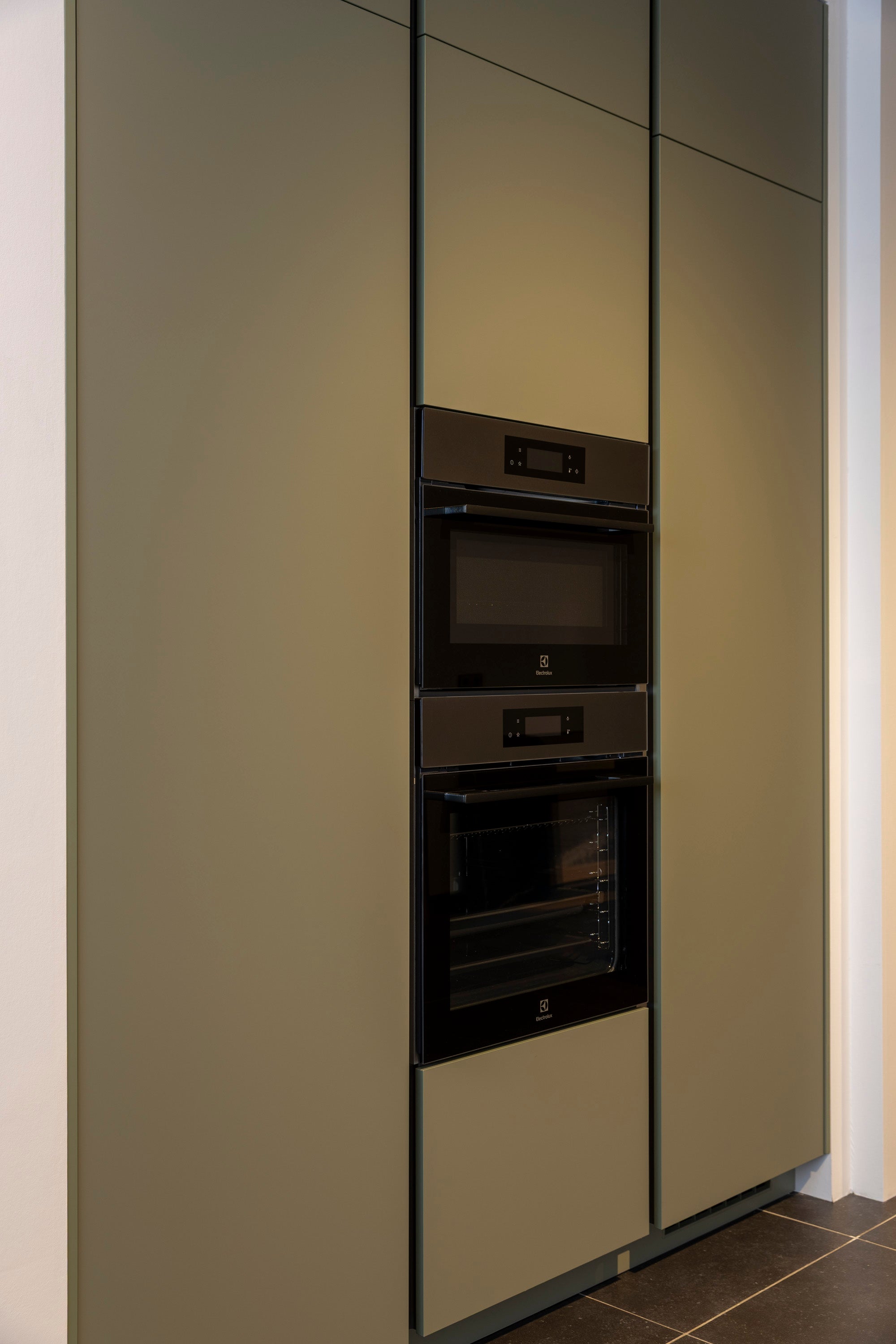 Olijfkleurige lakkeuken in hoekopstelling met Oscura composiet werkblad