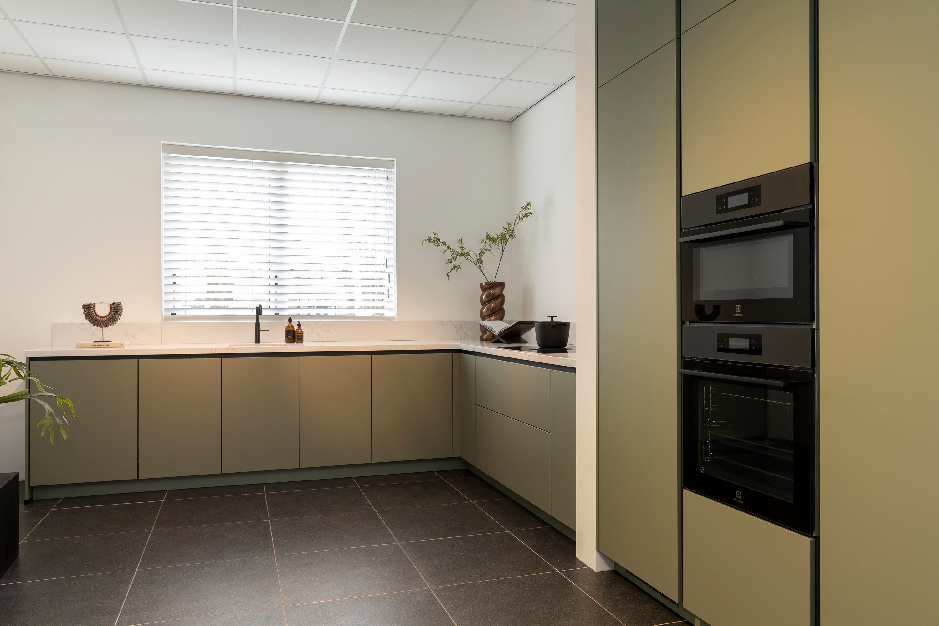 Olijfkleurige lakkeuken in hoekopstelling met Oscura composiet werkblad