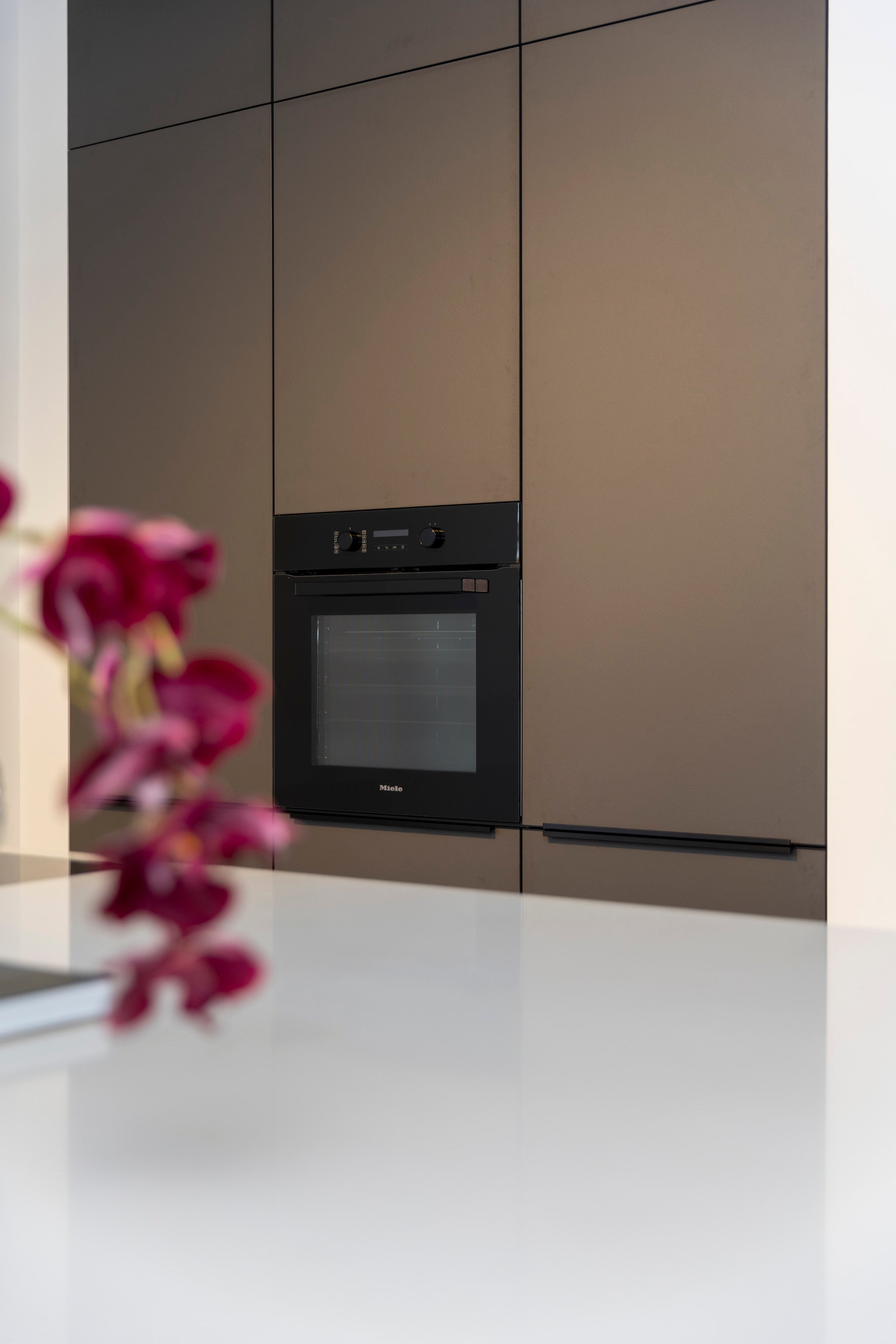 Coffee-kleur fronten met composiet werkblad en Miele-apparatuur