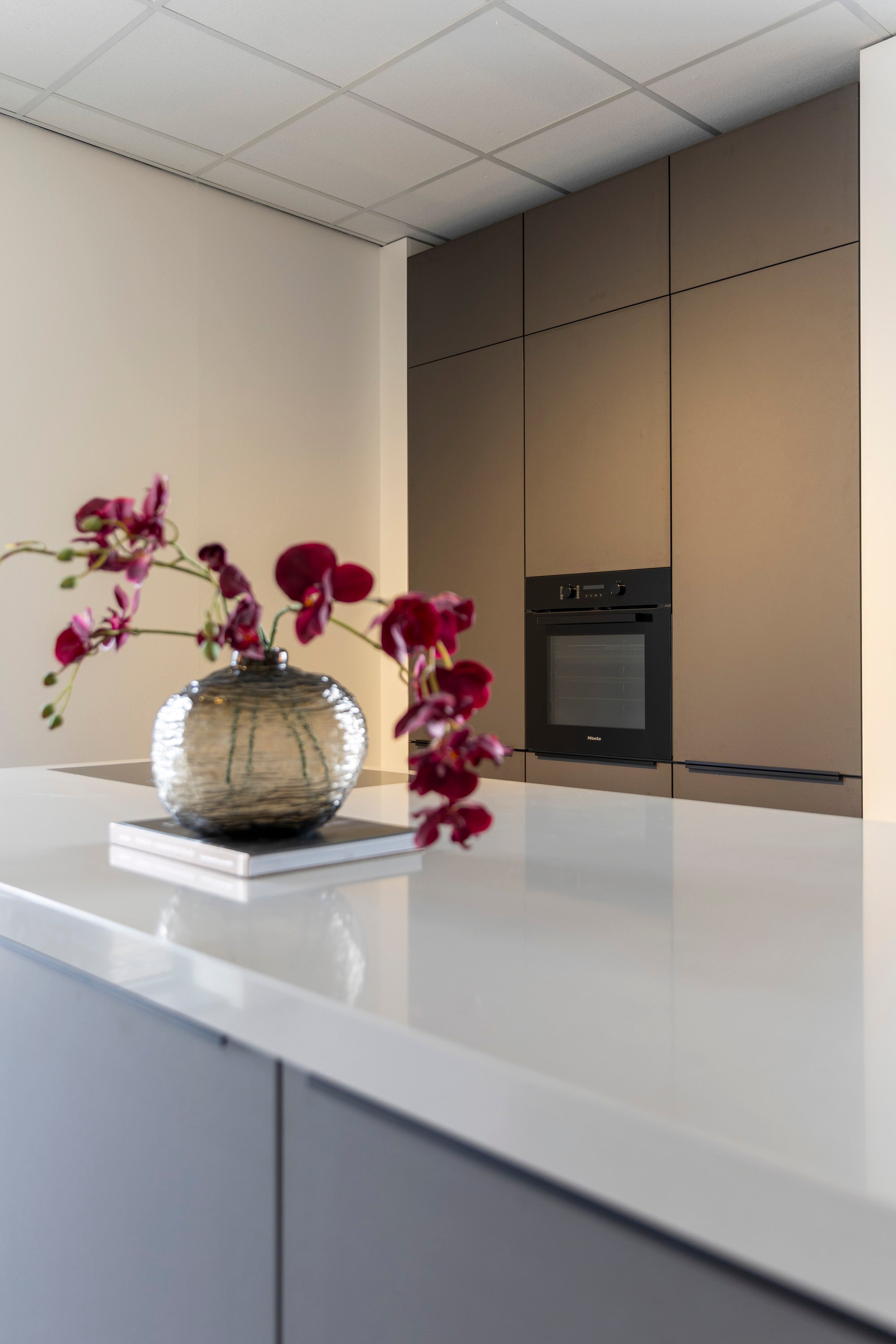 Coffee-kleur fronten met composiet werkblad en Miele-apparatuur