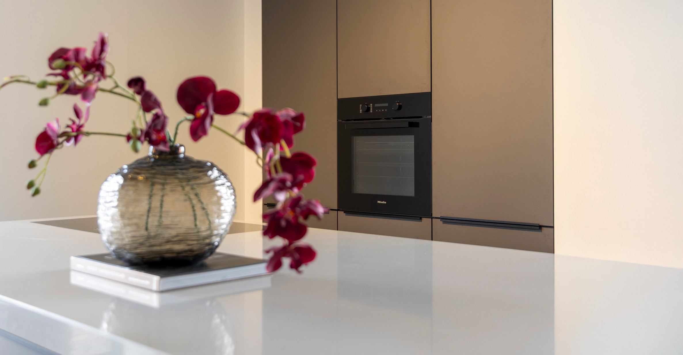 Coffee-kleur fronten met composiet werkblad en Miele-apparatuur